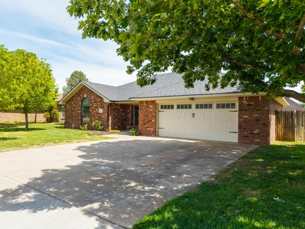 a view of a house with a yard and large tree