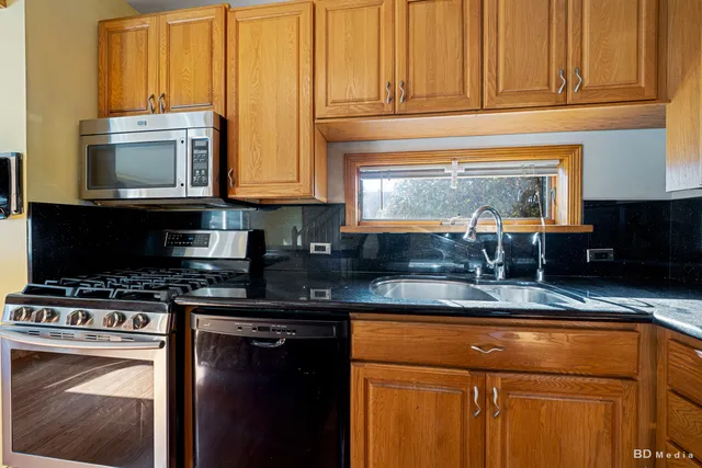 a kitchen with stainless steel appliances granite countertop a stove a sink and a microwave