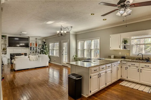 a large kitchen with kitchen island a stove a sink a center island and wooden floor