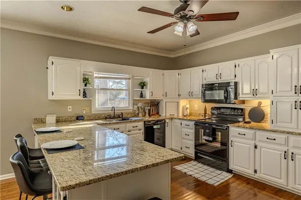 a kitchen with granite countertop a sink a stove a oven a dining table and chairs