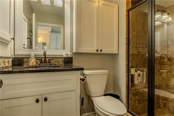 a bathroom with a granite countertop toilet sink and shower