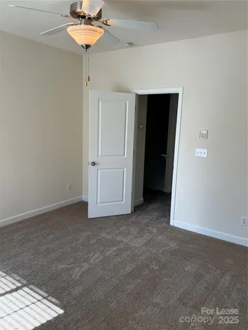 an empty room with a chandelier fan and closet