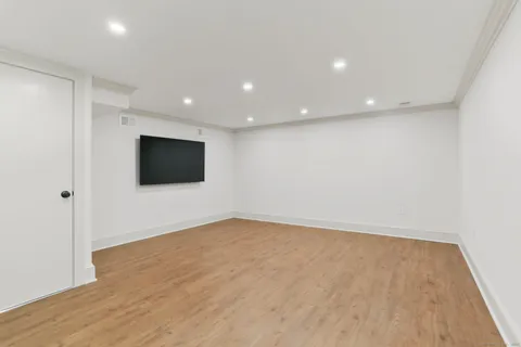 a view of an empty room with wooden floor and windows