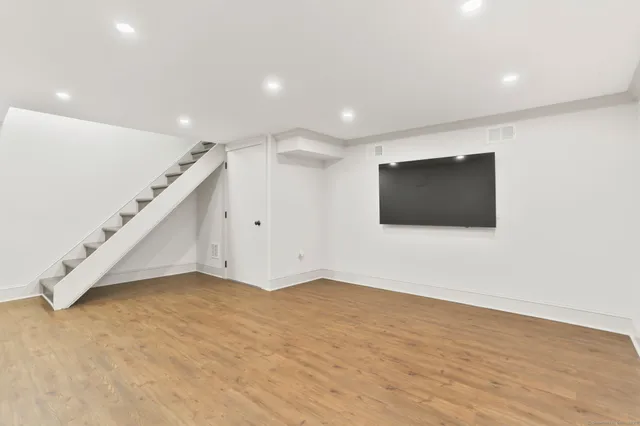 a view of an empty room with wooden floor and stairs