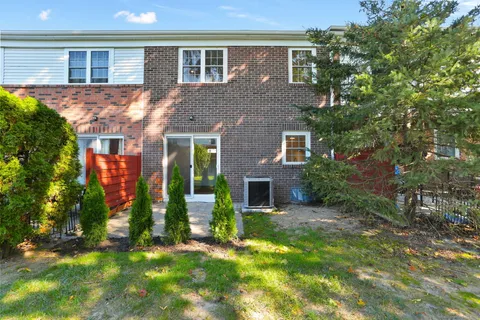 a view of a house with brick walls and a yard with plants