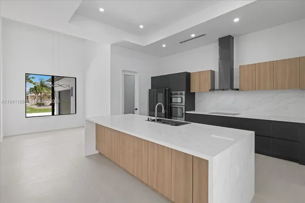 a large kitchen with stainless steel appliances a large counter top a stove a sink and a refrigerator