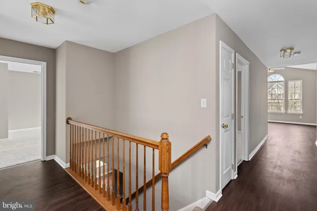 a view of a hallway with wooden floor and stairs