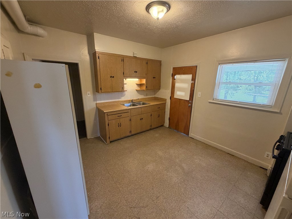 15300 Waterloo Road, Unit 1 Cleveland, OH 44110 - Photo 3 of 11 Kitchen featuring light wood-finish cabinetry, a double basin stainless steel sink, and a window with horizontal blinds