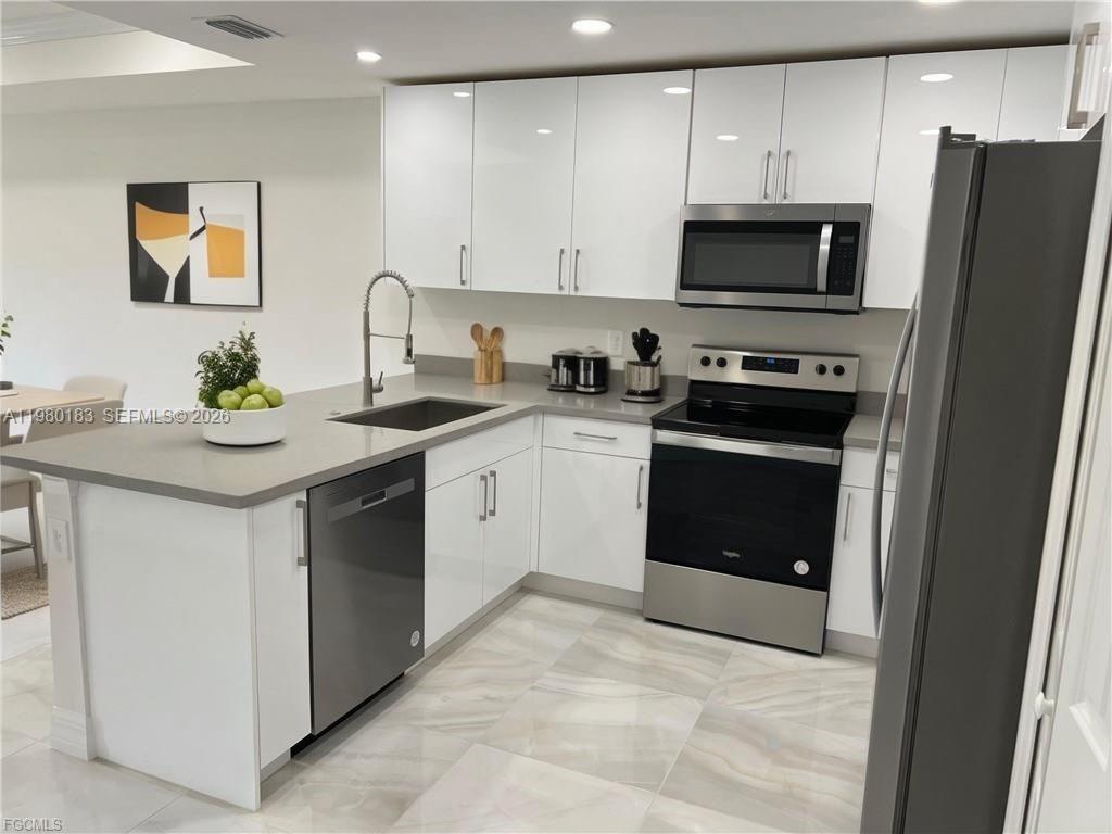 4854 30th Street Southwest, Unit 4854 Lehigh Acres, FL 33973 - Photo 3 of 11 a kitchen with stainless steel appliances granite countertop a stove a sink and a microwave