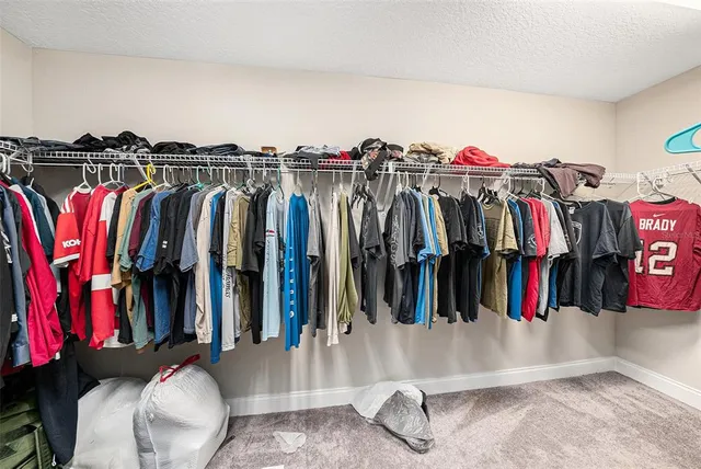a view of walk in closet with clothes and shoes
