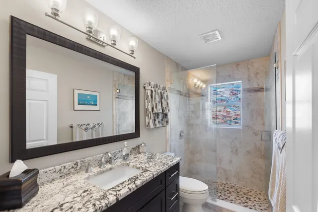 a bathroom with a granite countertop sink toilet a large mirror and shower