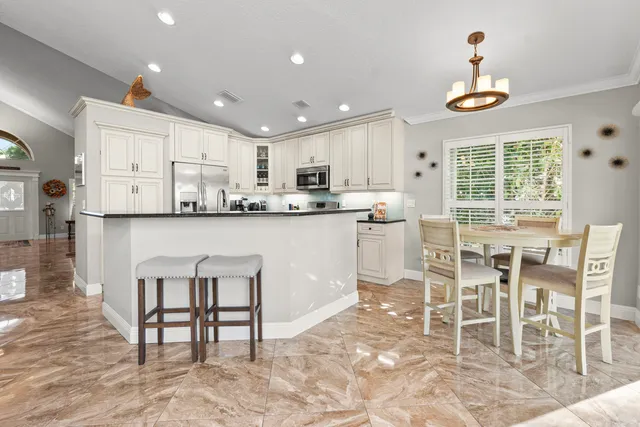 a kitchen with stainless steel appliances granite countertop a table and chairs in it