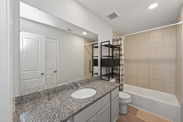 a bathroom with a granite countertop sink toilet and shower
