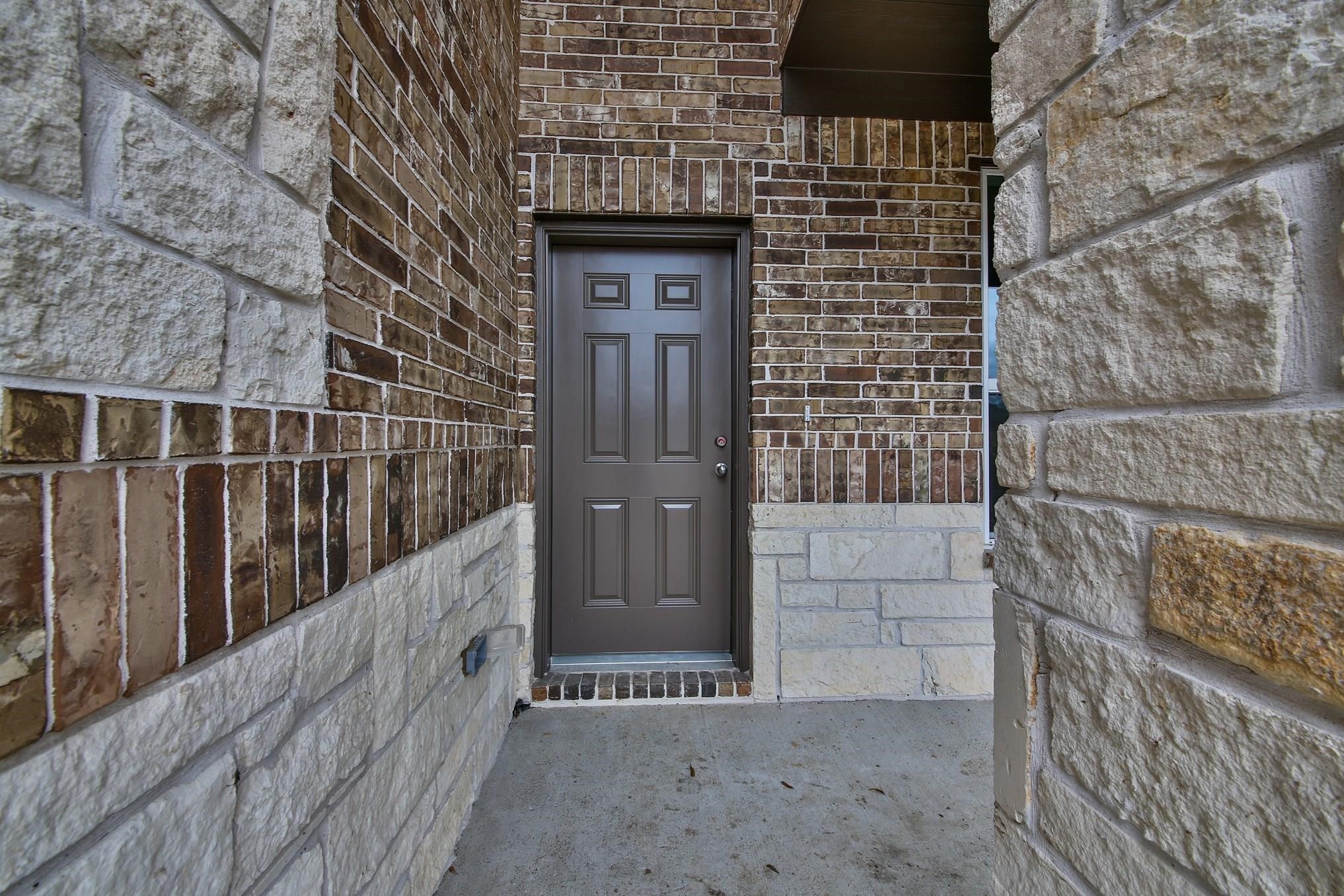 11355 Cascading Stream Way Houston, TX 77044 - Photo 2 of 17 Charming entrance with a sturdy brown door framed by elegant brick and stonework, offering a warm welcome to your new home.