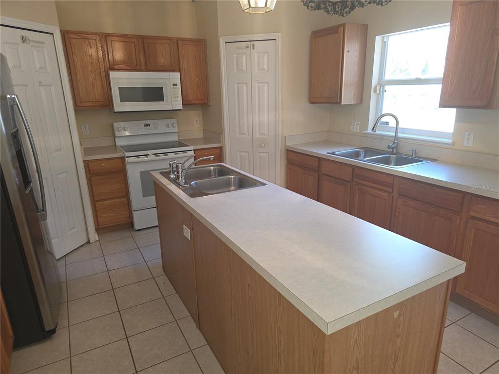 10563 Marysville Street Spring Hill, FL 34608 - Photo 4 of 22 a kitchen that has a sink a microwave a stove and a refrigerator