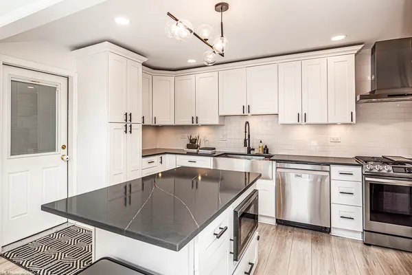 a kitchen with stainless steel appliances granite countertop a sink a stove and a refrigerator