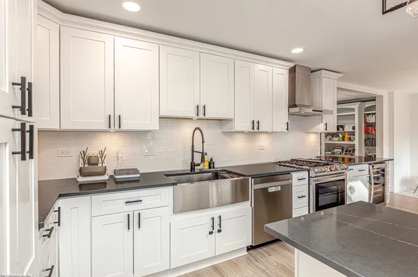 a kitchen with stainless steel appliances granite countertop a stove a sink and white cabinets