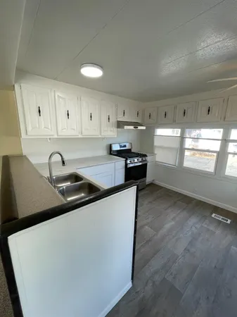 a kitchen with stainless steel appliances granite countertop a refrigerator a sink a stove and white cabinets