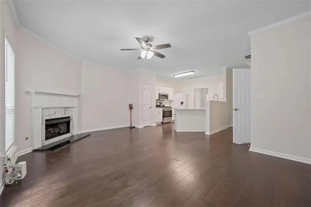 a view of an empty room with wooden floor and a fireplace