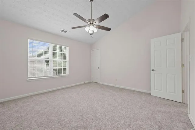an empty room with windows and fan
