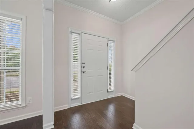 an empty room with wooden floor closet and windows