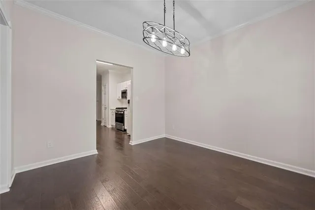 an empty room with wooden floor and chandelier