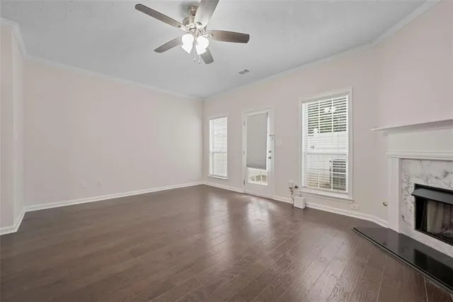 an empty room with wooden floor chandelier fan and windows