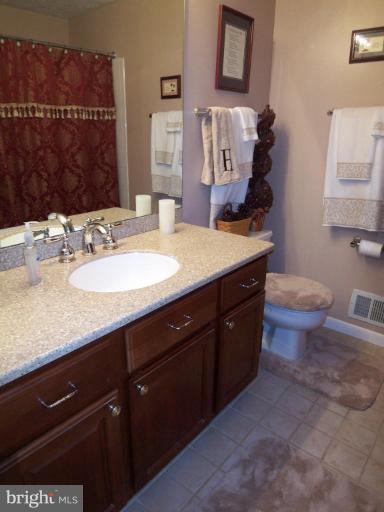 8060 Athena Street Springfield, VA 22153 - Photo 14 of 21 a bathroom with a granite countertop sink a toilet and mirror