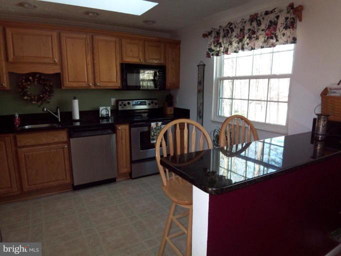 8060 Athena Street Springfield, VA 22153 - Photo 7 of 21 a kitchen with granite countertop a stove a sink and a microwave