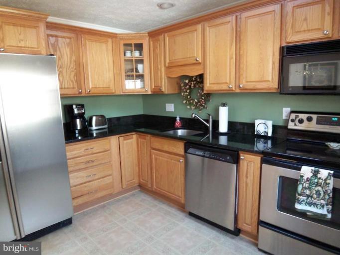 8060 Athena Street Springfield, VA 22153 - Photo 8 of 21 a kitchen with stainless steel appliances granite countertop a refrigerator sink and cabinets