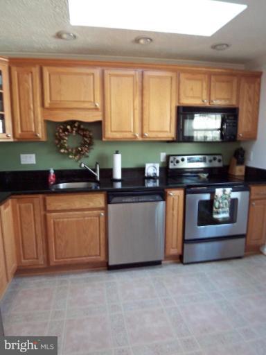 8060 Athena Street Springfield, VA 22153 - Photo 9 of 21 a kitchen with stainless steel appliances granite countertop a stove a sink and a microwave