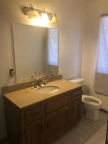 a bathroom with a granite countertop sink and a toilet