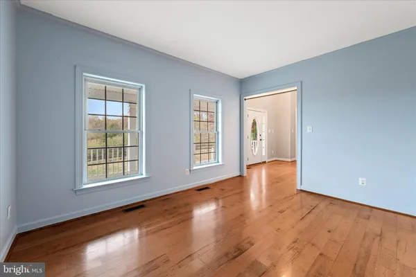 a view of empty room with wooden floor and windows