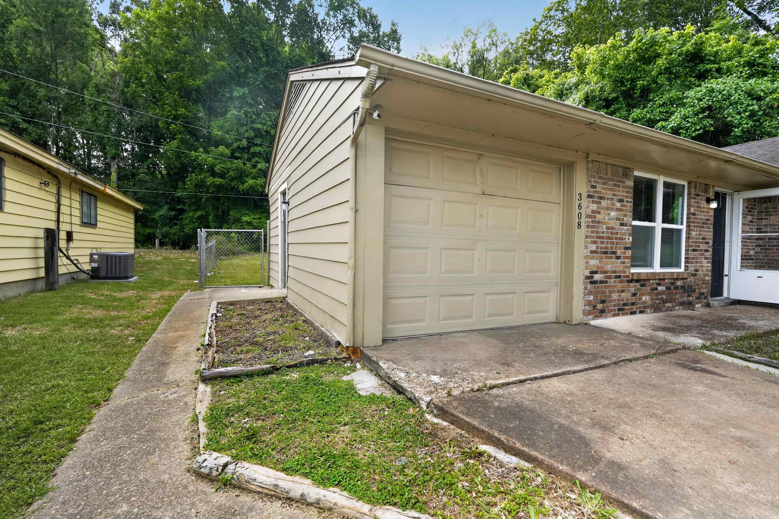 3608 Cane Ridge Drive Memphis, TN 38109 - Photo 3 of 31 Brick and siding exterior featuring an attached garage with a concrete driveway, a side entry door, and a privacy-fenced yard