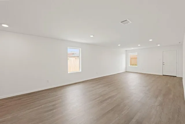 an empty room with wooden floor and windows