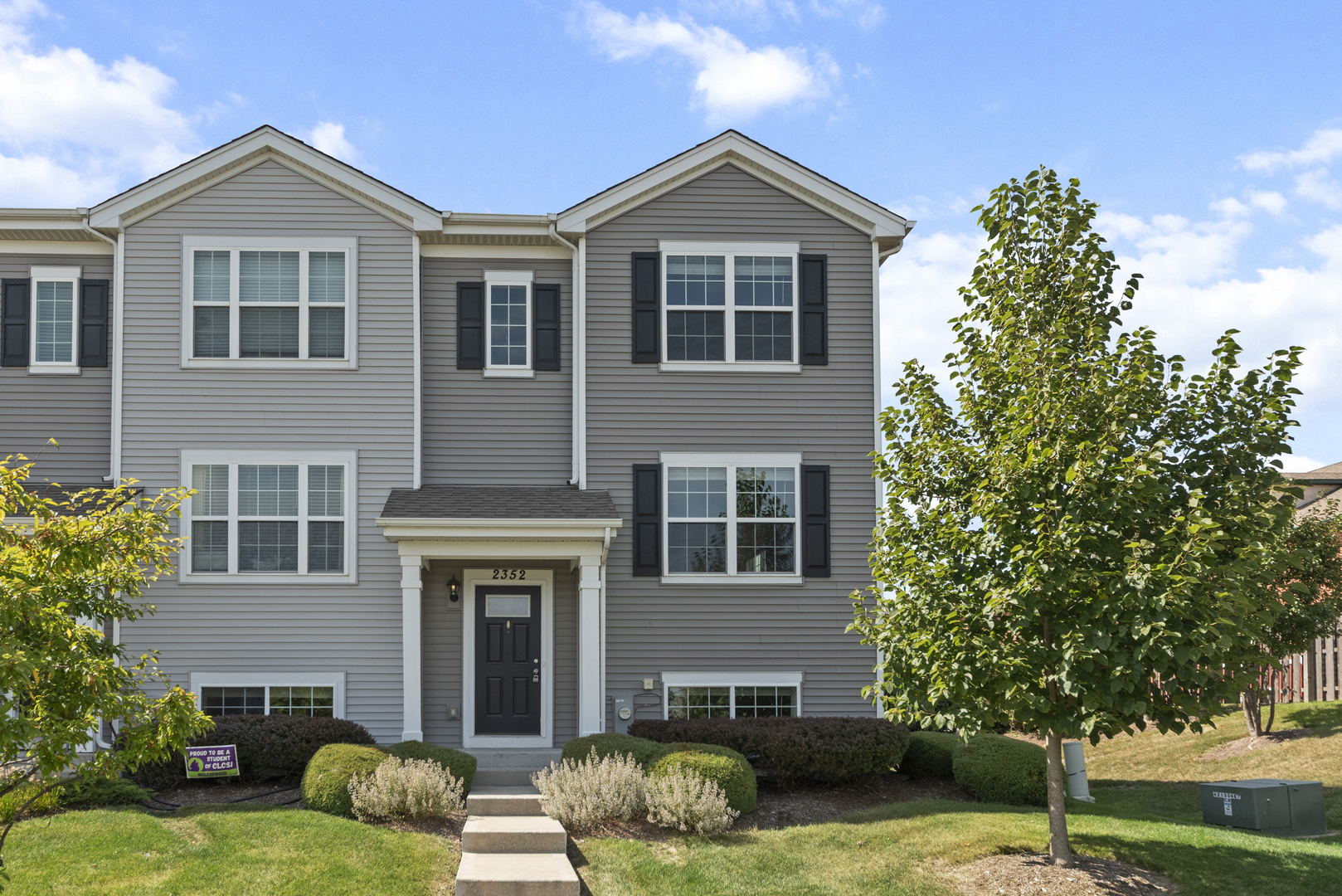 a front view of a house with garden and trees