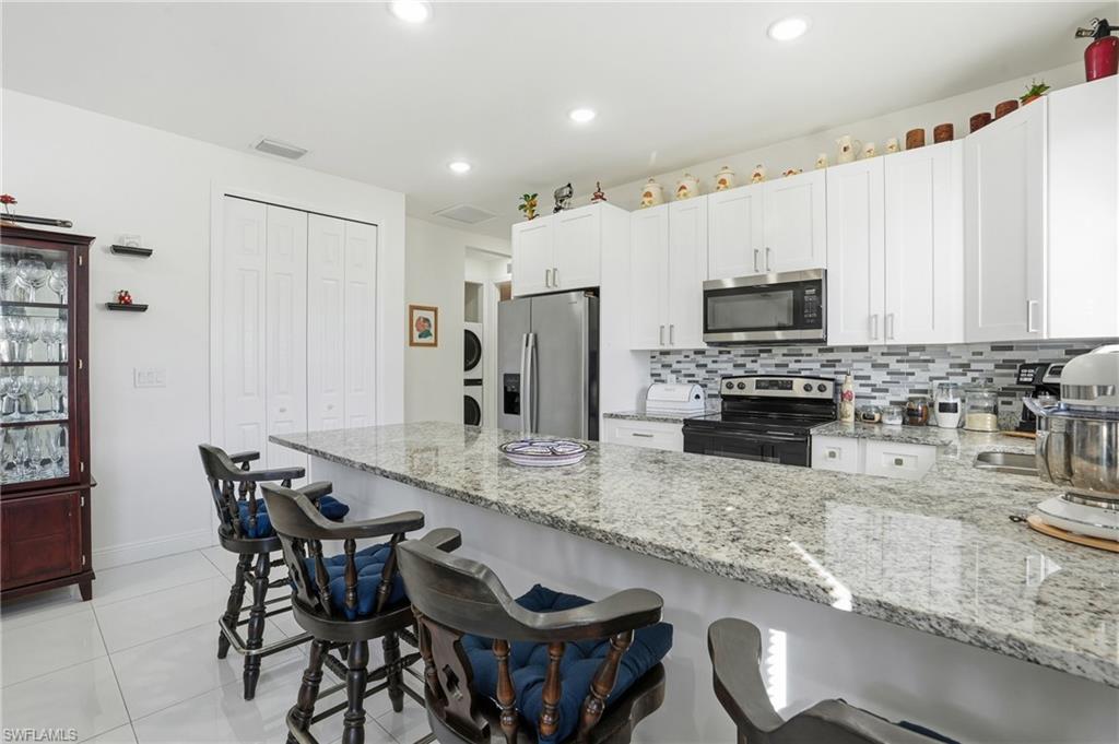 3409 64th Street West Lehigh Acres, FL 33971 - Photo 17 of 44 a kitchen with granite countertop a table chairs microwave and refrigerator