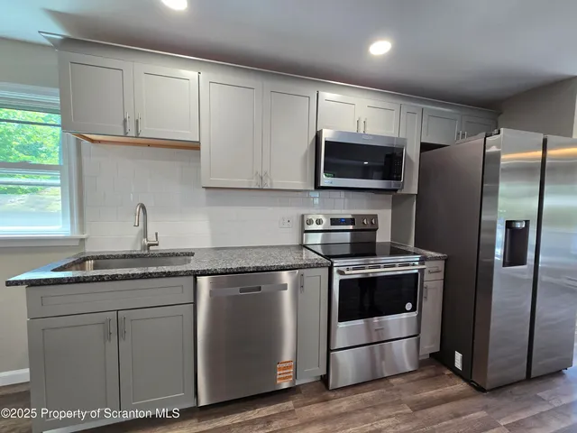 a kitchen with stainless steel appliances granite countertop a stove a refrigerator and a sink