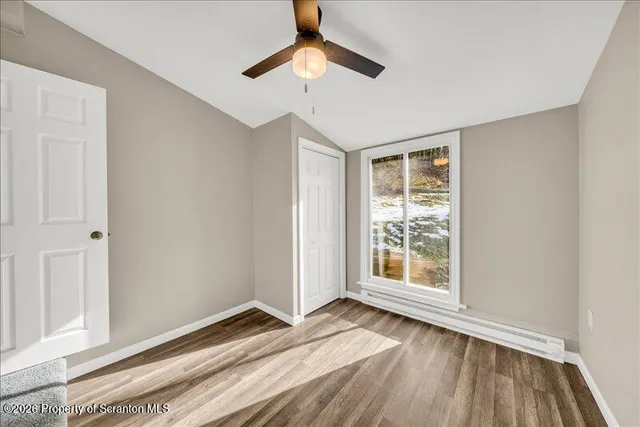 a view of an empty room with window and wooden floor