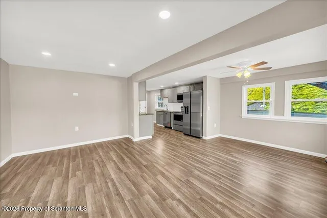 a view of empty room with wooden floor and window