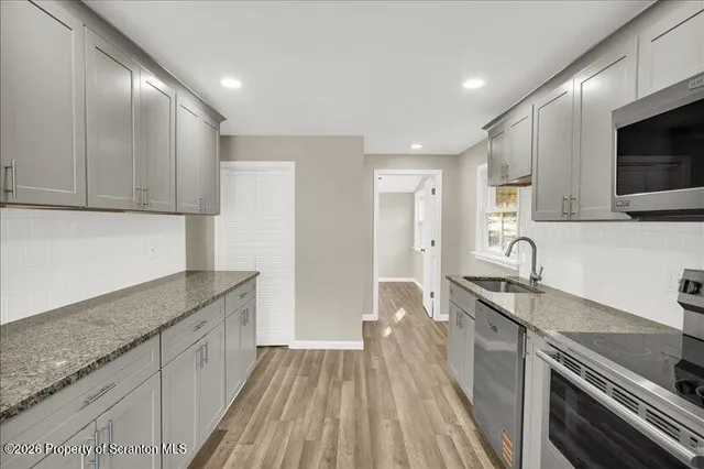 a kitchen with granite countertop a sink stainless steel appliances and cabinets