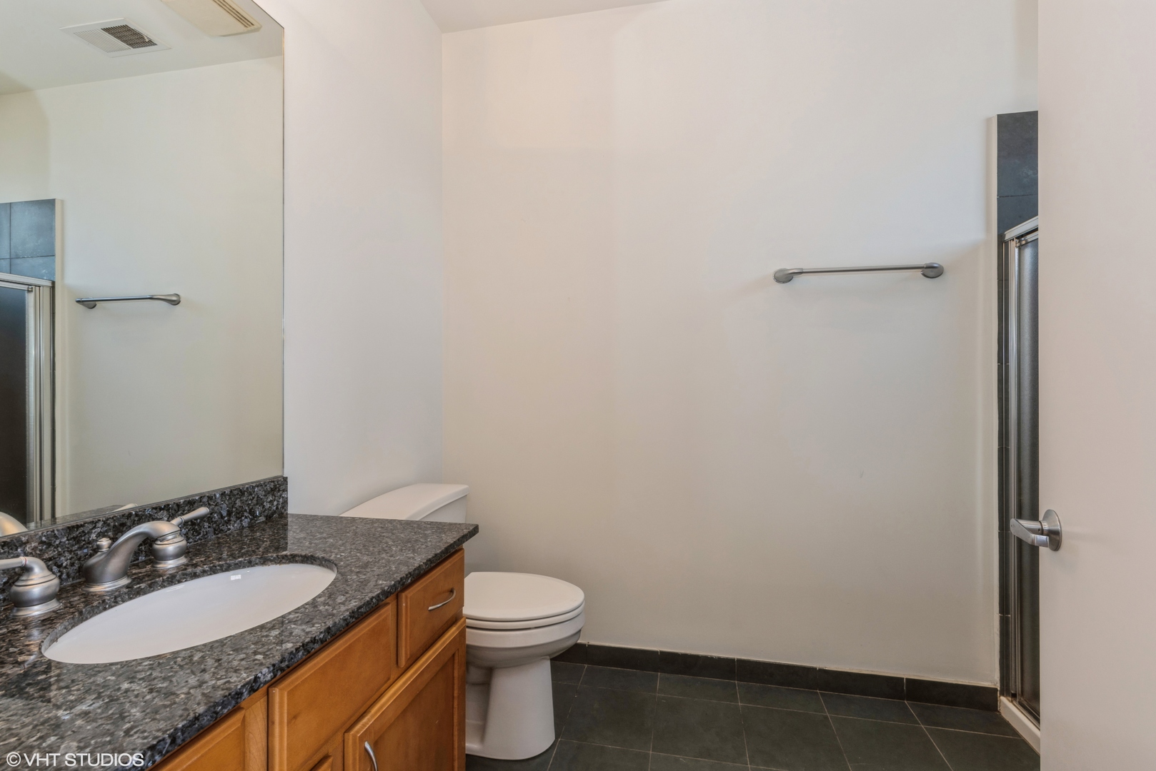 2510 West Irving Park Road, Unit 402 Chicago, IL 60618 - Photo 11 of 13 a bathroom with a granite countertop sink toilet and a mirror