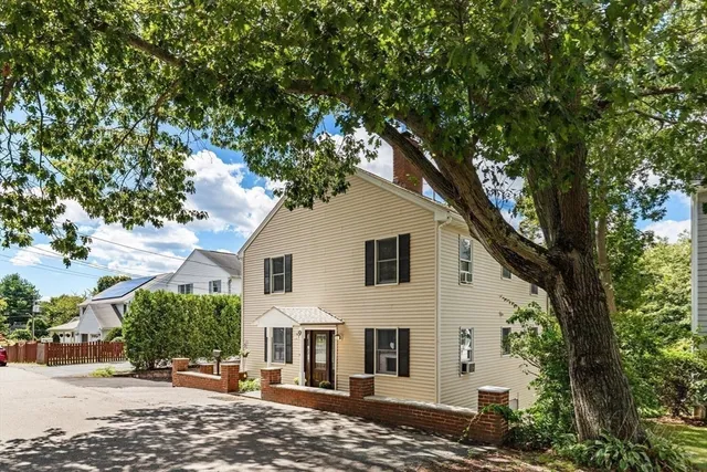 a view of a white house with a large tree