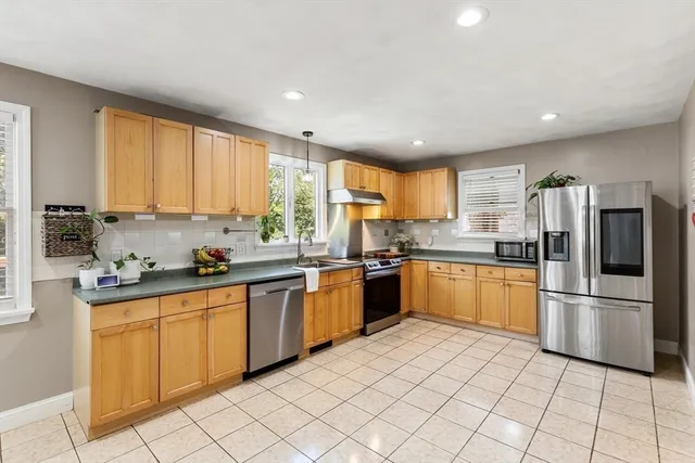 a kitchen with stainless steel appliances granite countertop a stove a sink a dining table and chairs with wooden floor
