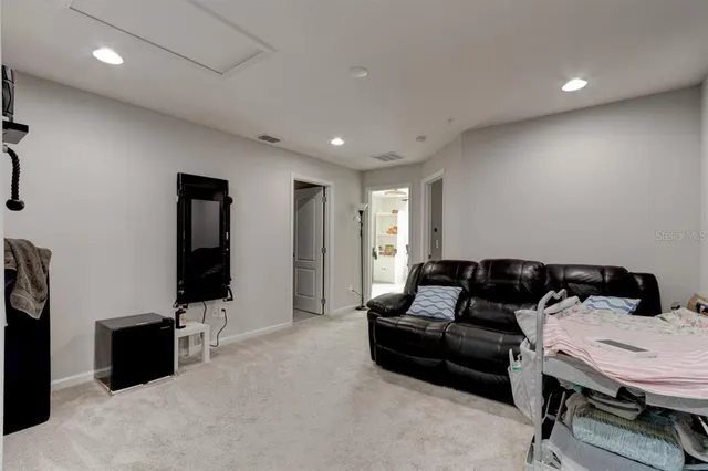 a living room with furniture a flat screen tv and a refrigerator