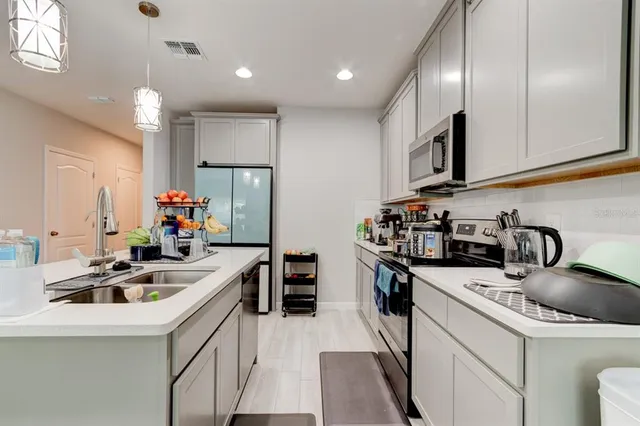 a kitchen that has a lot of cabinets a sink and appliances