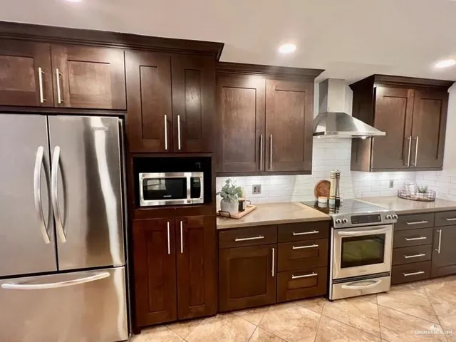 a kitchen with stainless steel appliances granite countertop a refrigerator a sink and wooden cabinets