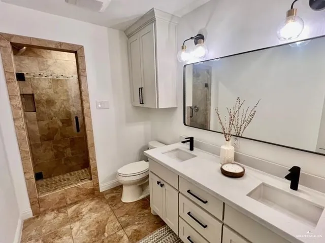 a bathroom with a double vanity sink mirror and shower