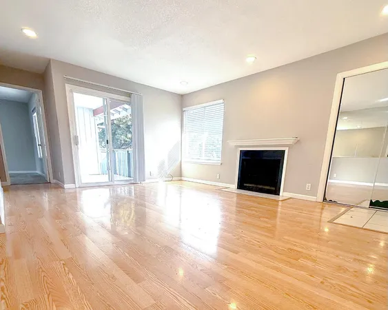 a view of empty room with wooden floor and fireplace