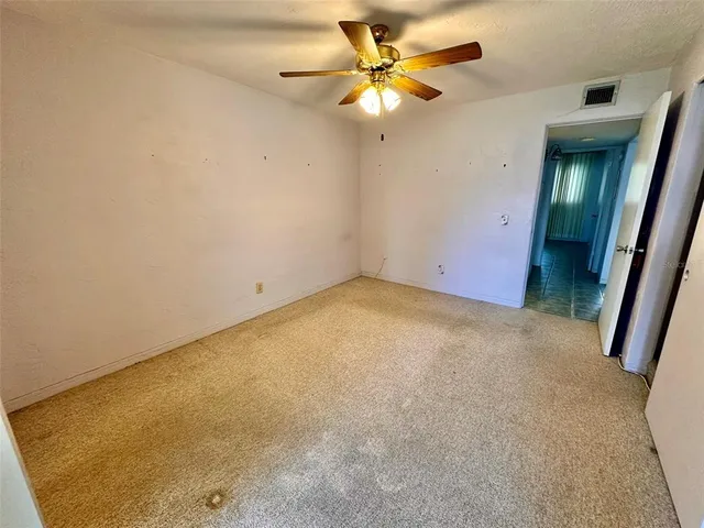 an empty room with a chandelier fan and a large window